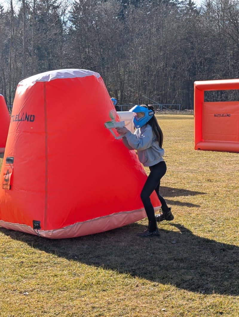 Holka míří gel blasterem u nafukovačky